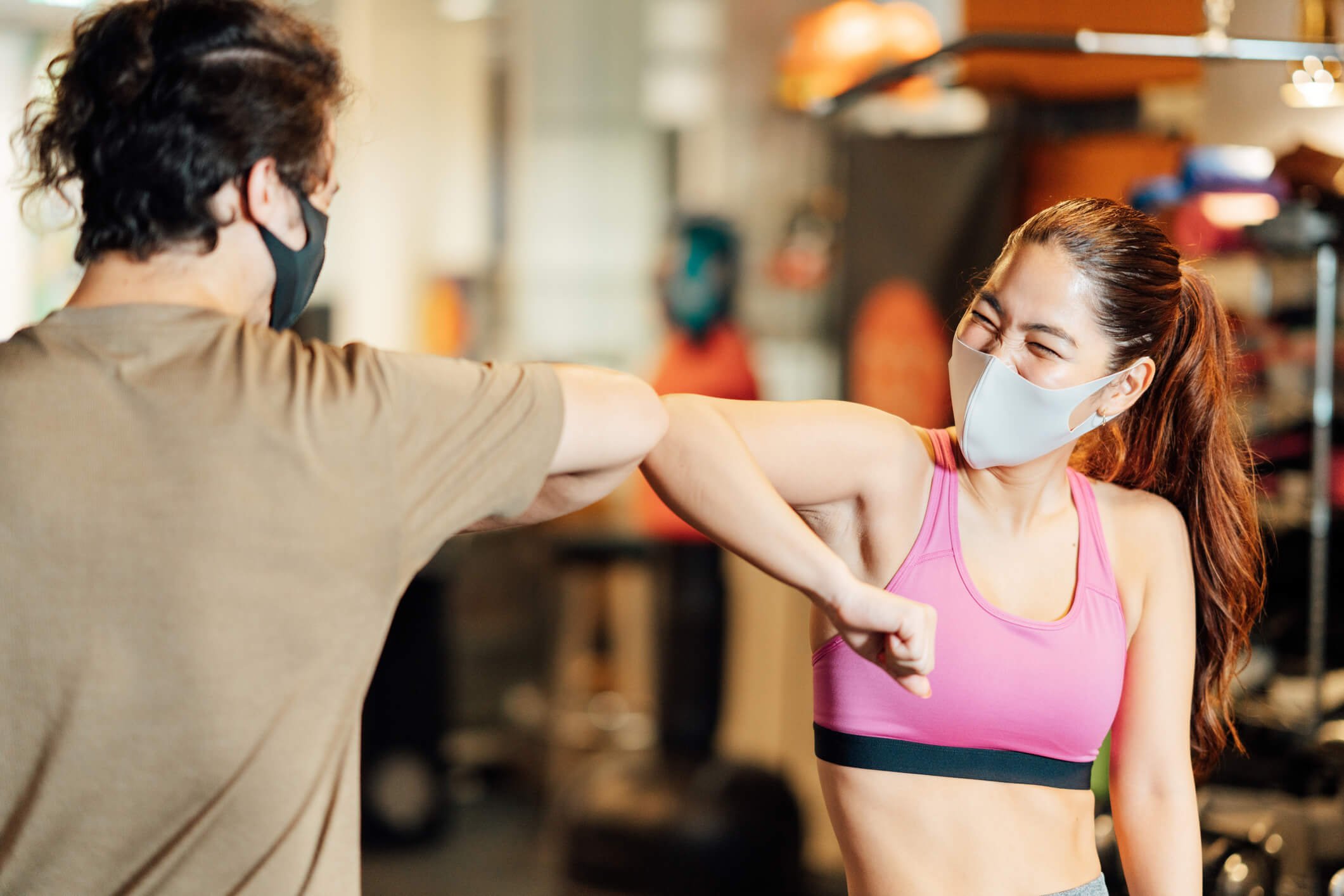 2 athletes elbow bumping good job at gym in masks